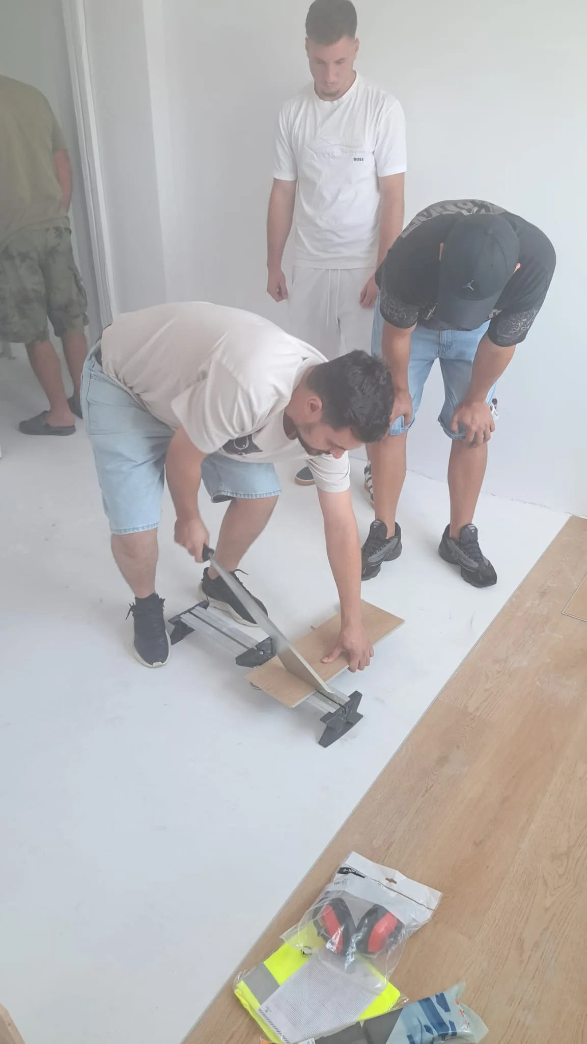 Participanți lucrând la montajul parchetului sub îndrumare